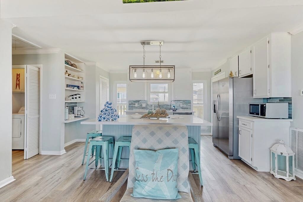 A modern kitchen with white cabinetry, a central island, and bar stools.