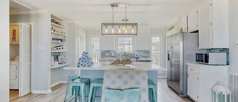 A modern kitchen with white cabinetry, a central island, and bar stools.