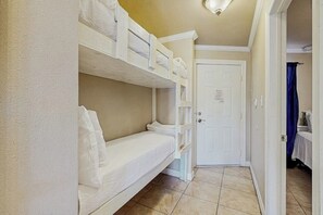 A room with bunk beds, a white door, and a tiled floor. - Beachside Escape - Gulf-Front Condo with Pool (Galveston)