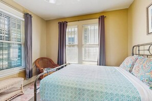 Ein Schlafzimmer mit einem Bett, einem Sessel, einem Fenster mit Jalousien und einer Heizung.