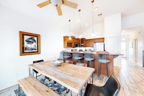 Eine moderne Küche mit Holzschränken, einer Bar und einem Esstisch mit Stühlen.
