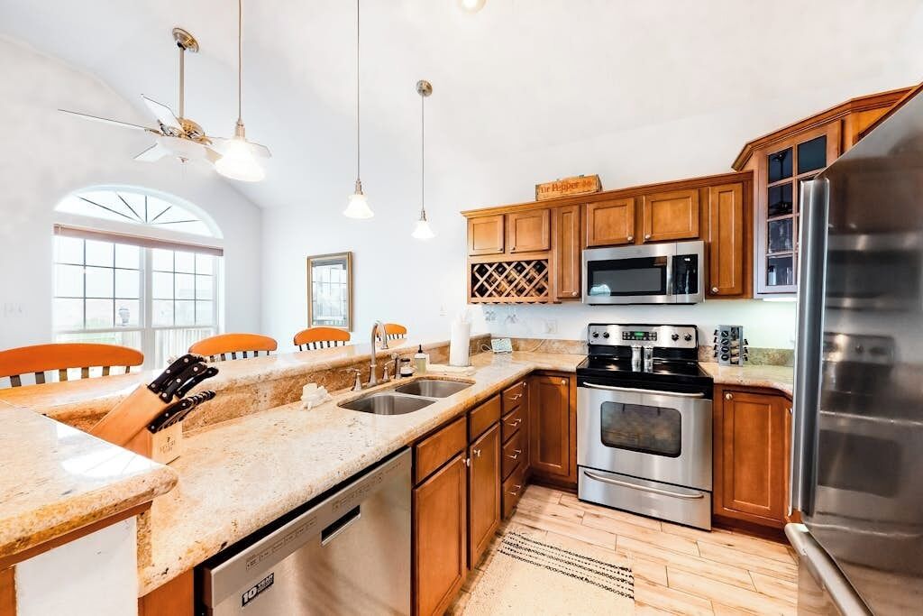 A kitchen with wooden cabinets, stainless steel appliances, a dishwasher, and a ceiling fan.