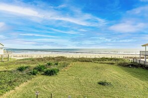 Ein Küsteneigentum mit Rasenfläche, Holzzaun und Blick auf den Strand.