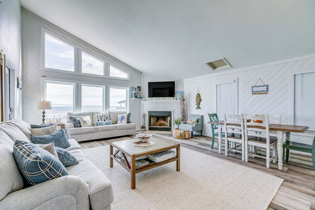 A spacious living room with a fireplace, a dining area, and large windows.