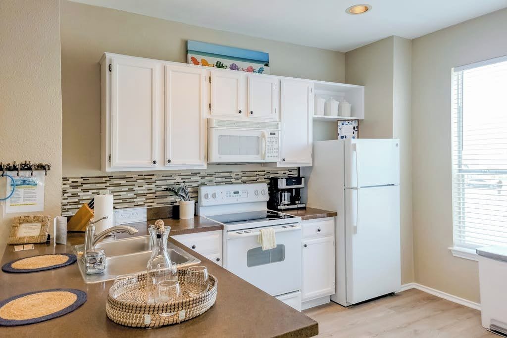 A modern kitchen with white cabinetry, a microwave, stove, and refrigerator.