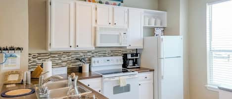 Una cocina moderna con armarios blancos, microondas, estufa y refrigerador.