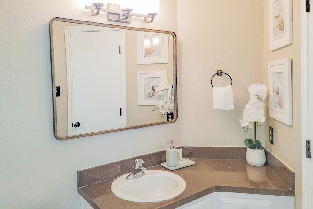 A bathroom with a large mirror, a sink, a towel rack, and framed pictures on the wall.