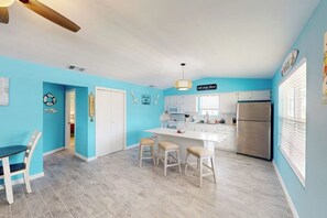 A kitchen with a central island, white cabinets, and a stainless steel refrigerator. - Padre Island Paradise on Hibiscus (South Padre Island)
