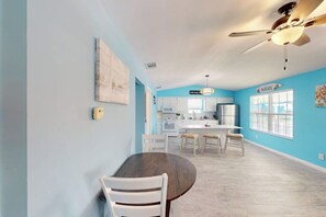A spacious kitchen with white cabinets, a central island, and a ceiling fan. - Padre Island Paradise on Hibiscus (South Padre Island)