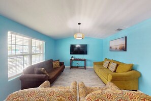 A living room with two sofas, a flat-screen TV, and a patterned rug. - Padre Island Paradise on Hibiscus (South Padre Island)