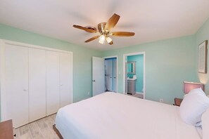 A bedroom with a bed, a ceiling fan, a wardrobe, and a bathroom with a mirror. - Padre Island Paradise on Hibiscus (South Padre Island)