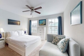 A bedroom with a bed, a nightstand, a dresser, a ceiling fan, and a window with curtains. - Beach & Chill at 109 E Dolphin (South Padre Island)
