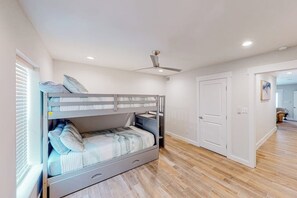 Ein Zimmer mit Etagenbett, Deckenventilator und einer Tür zu einem anderen Raum.