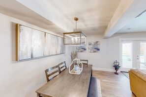 Een eethoek met een houten tafel, stoelen en een hanglamp.
