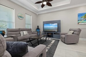 A modern living room with a flat-screen TV, grey sofas, a coffee table, and a decorative vase. - Retama Landing #3 - Pool & Balcony, Walk to Beach (South Padre Island)