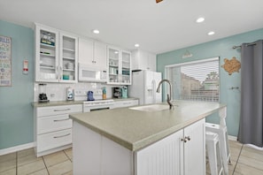 A kitchen with white cabinets, a sink, and a window with blinds. - Island Escape Unit B (South Padre Island)