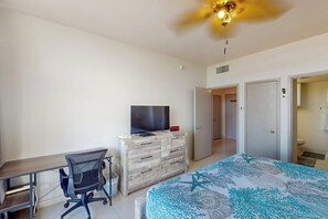 Een slaapkamer met een bed, een bureau, een stoel, een televisie en een kledingkast.