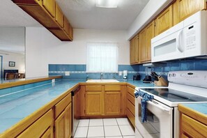 A kitchen with wooden cabinets, a white stove, and a microwave. - Mars Island Unit B - Private Pool, Walk to Beach (South Padre Island)