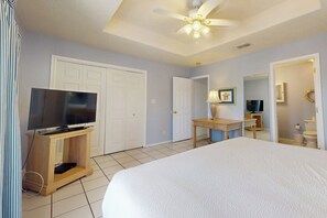 A hotel room with a bed, a television on a wooden stand, a ceiling fan, and a bathroom visible through an open door. - Mars Island Unit B - Private Pool, Walk to Beach (South Padre Island)