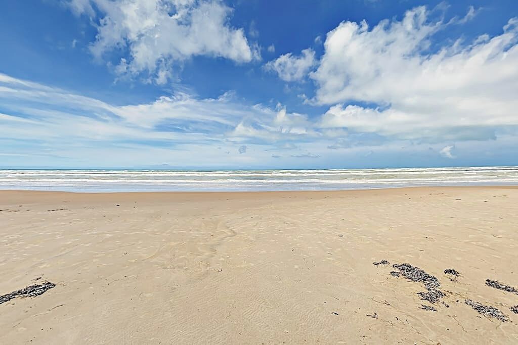 Una playa con cielo despejado y mar tranquilo.