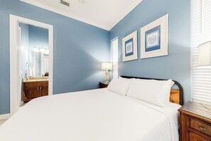 A bedroom with a large bed, a nightstand, a lamp, and a dresser. - Saturn Serenity 1 - Shared Pool & Dog-Friendly (South Padre Island)