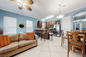 A compact living space with a kitchenette, a dining area, and a sofa with orange cushions. - Saturn Serenity 1 - Shared Pool & Dog-Friendly (South Padre Island)