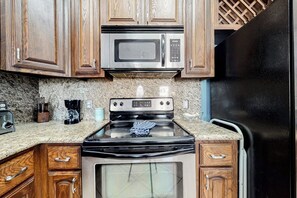 Une cuisine avec des meubles en bois, un four à micro-ondes en acier inoxydable, une cuisinière et un réfrigérateur.