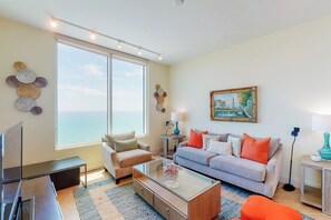 A modern living room with a sofa, coffee table, and a TV. - Sapphire Condominiums #2701 (South Padre Island)