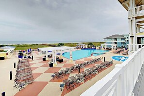 Ein Poolbereich mit Liegestühlen und einer überdachten Sitzgelegenheit mit Blick auf einen Strand.