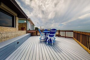 A wooden deck with a table and chairs, overlooking a body of water. - Anchors Away at North Shore (Port Isabel)