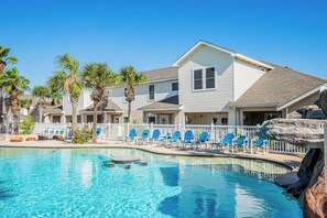 A hotel with a swimming pool, lounge chairs, and palm trees. - Palm Bay - Pelican Perch (Corpus Christi)