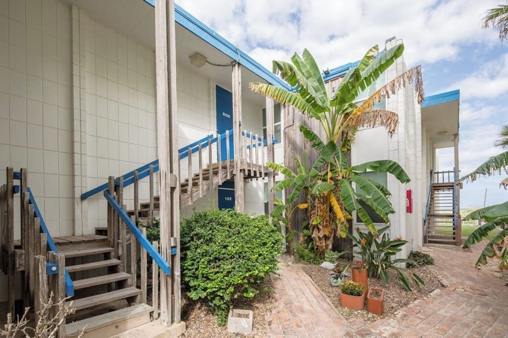 A building with a staircase, a blue railing, and a brick pathway.