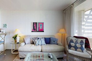 Uma sala de estar com sofá, poltronas, mesa de centro e obras de arte nas paredes.