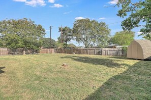 A backyard with a fenced area, a shed, and trees. - Corpus Christi Charm (Corpus Christi)