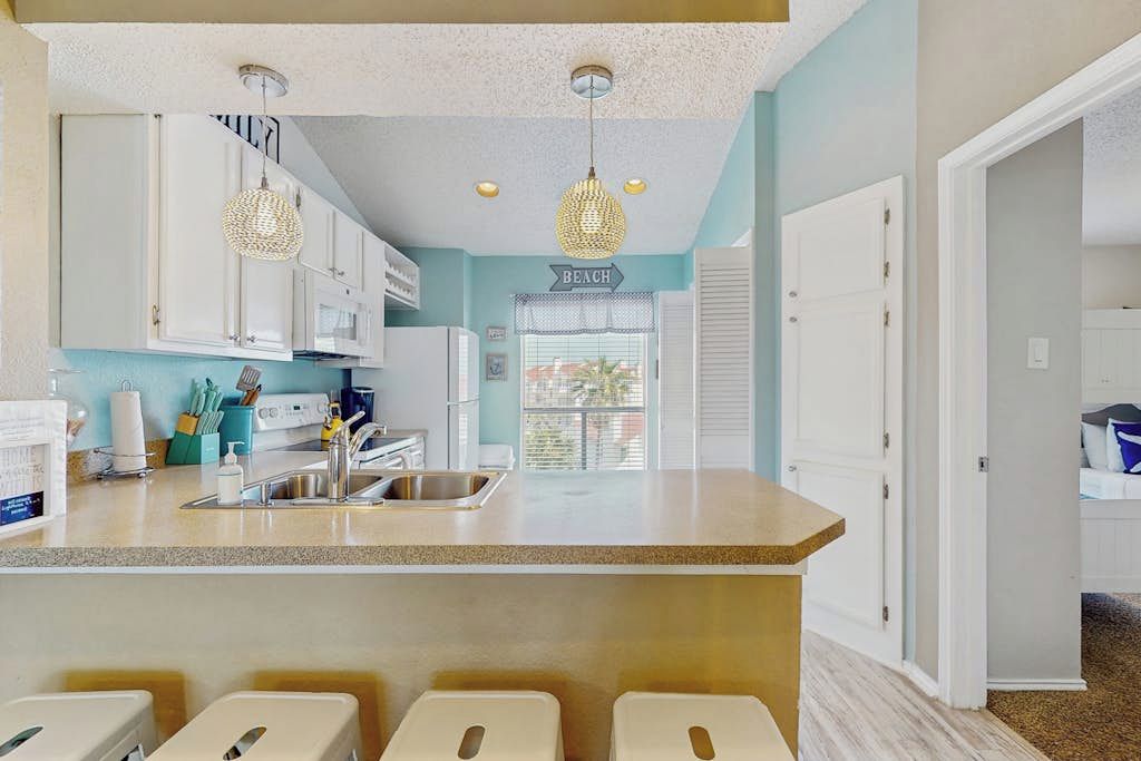 Una cocina con armarios blancos, una encimera y un cartel que dice 'BEACH'.