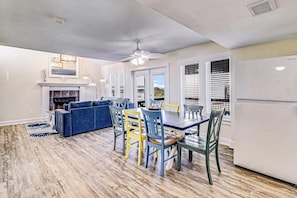 A modern kitchen with a dining area, a fireplace, and a ceiling fan. - Wine & Waves - Gulf Views, 400 Feet to Beach (Port Aransas)