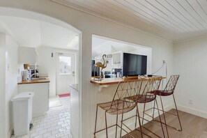 A modern kitchen with a central island, bar stools, and a flat-screen TV. - El Cerrito Place - Rooftop Deck & Historic Charm (Port Aransas)