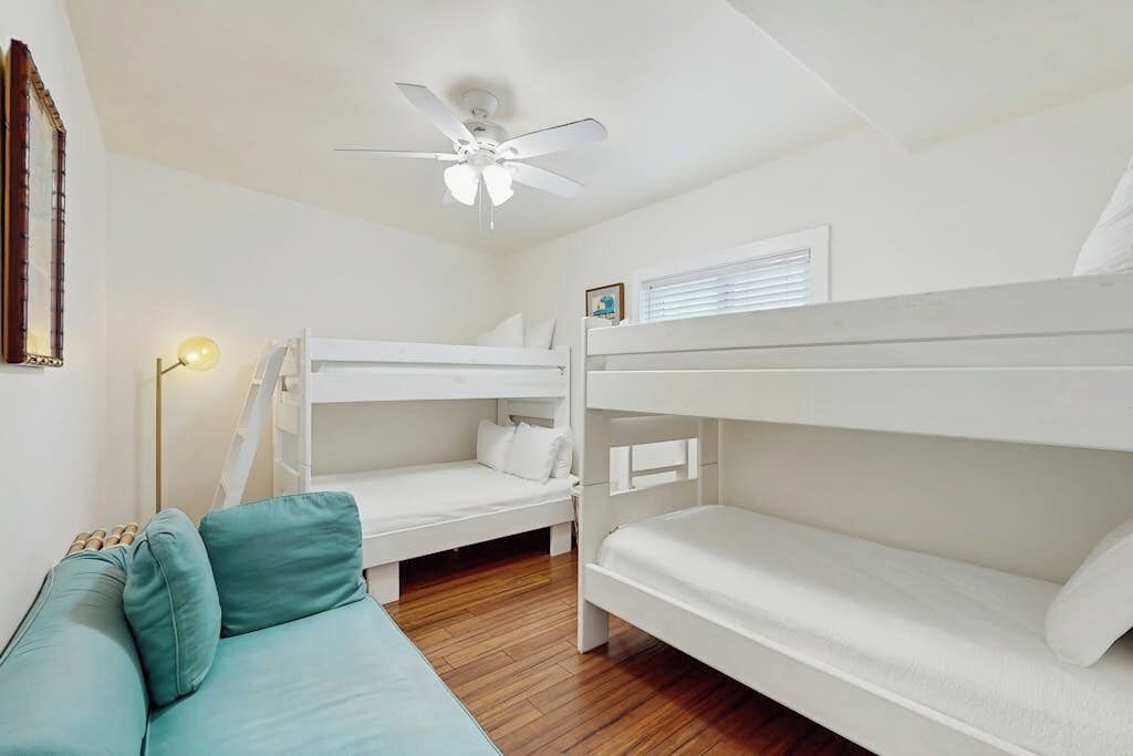 Una habitación con literas, ventilador de techo, un cuadro enmarcado e iluminación.