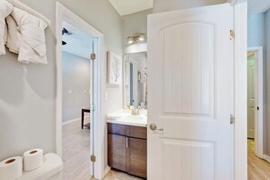 Ein Badezimmer mit einer weißen Toilette, einem Waschbecken mit Spiegel und einem Handtuchhalter.