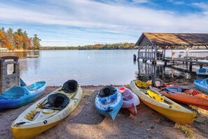 A lakeside dock with kayaks and a covered structure.