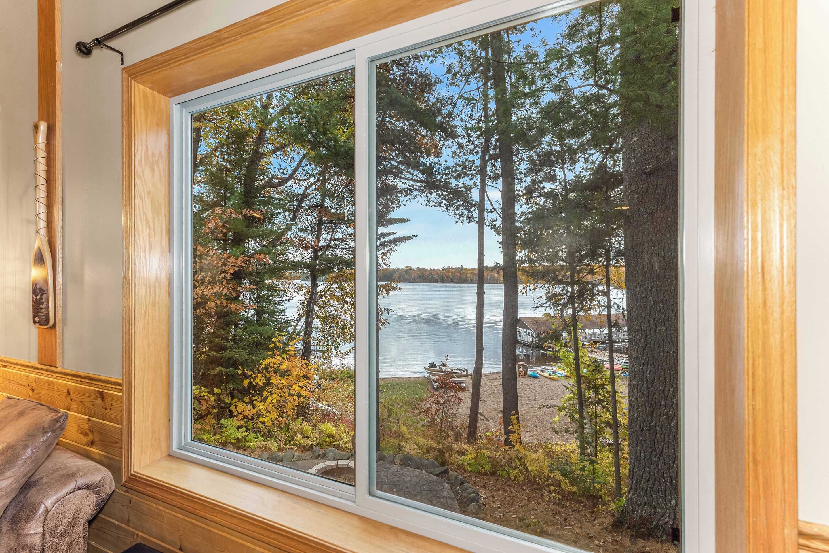 A room with a large window overlooking a lake and forest.