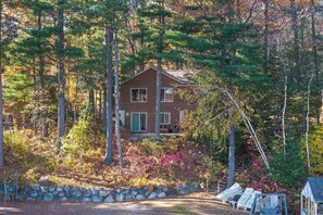 A cabin surrounded by a stone wall and trees with autumn foliage.