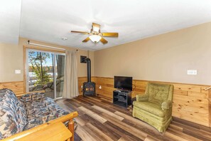 Uma sala de estar aconchegante com sofá, poltrona verde, lareira e ventilador de teto.
