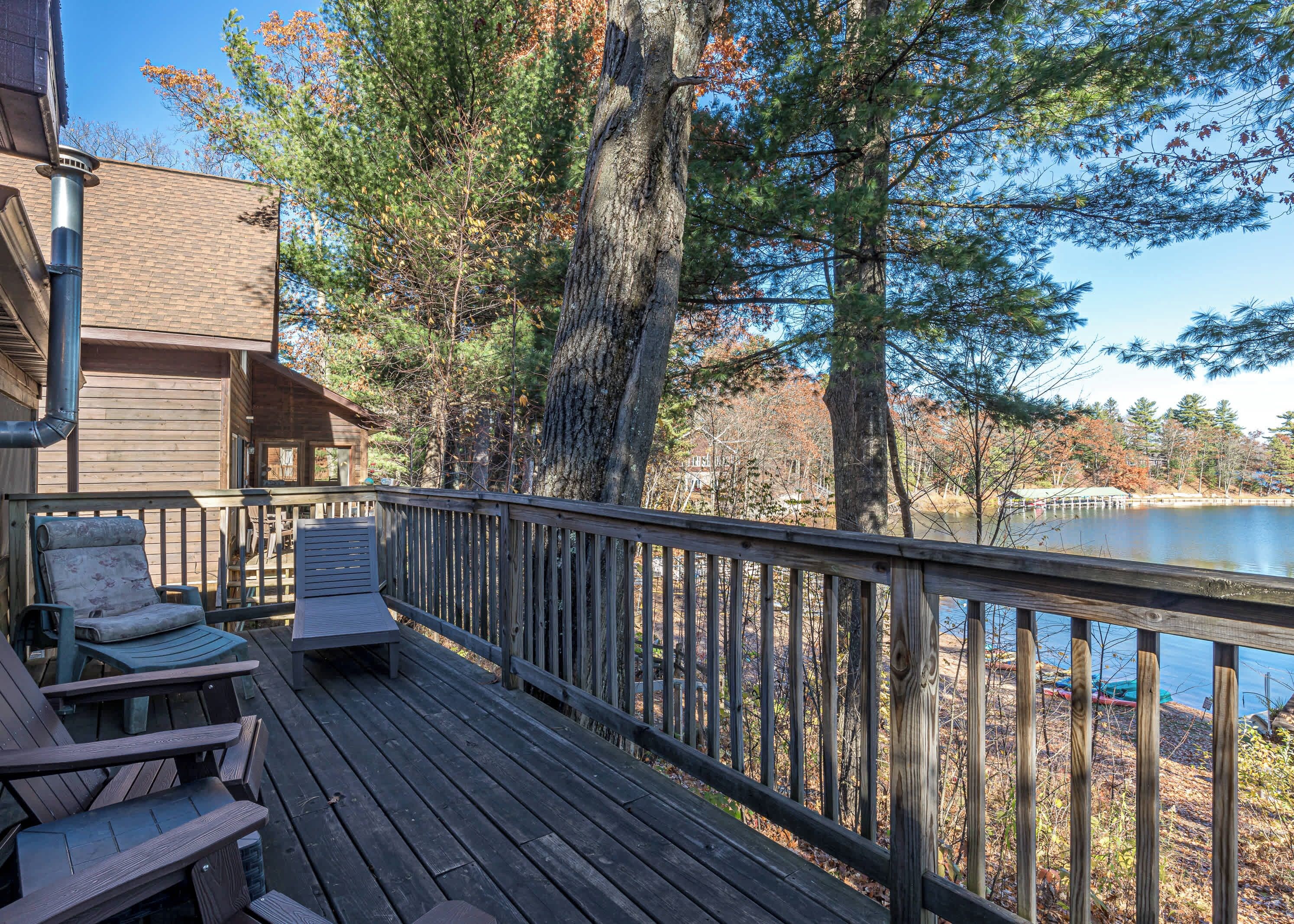 A wooden deck with outdoor seating and a view of a lake surrounded by trees.