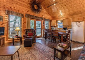 Interior acolhedor de uma cabana com área de refeições, cozinha e espaço para sentar.