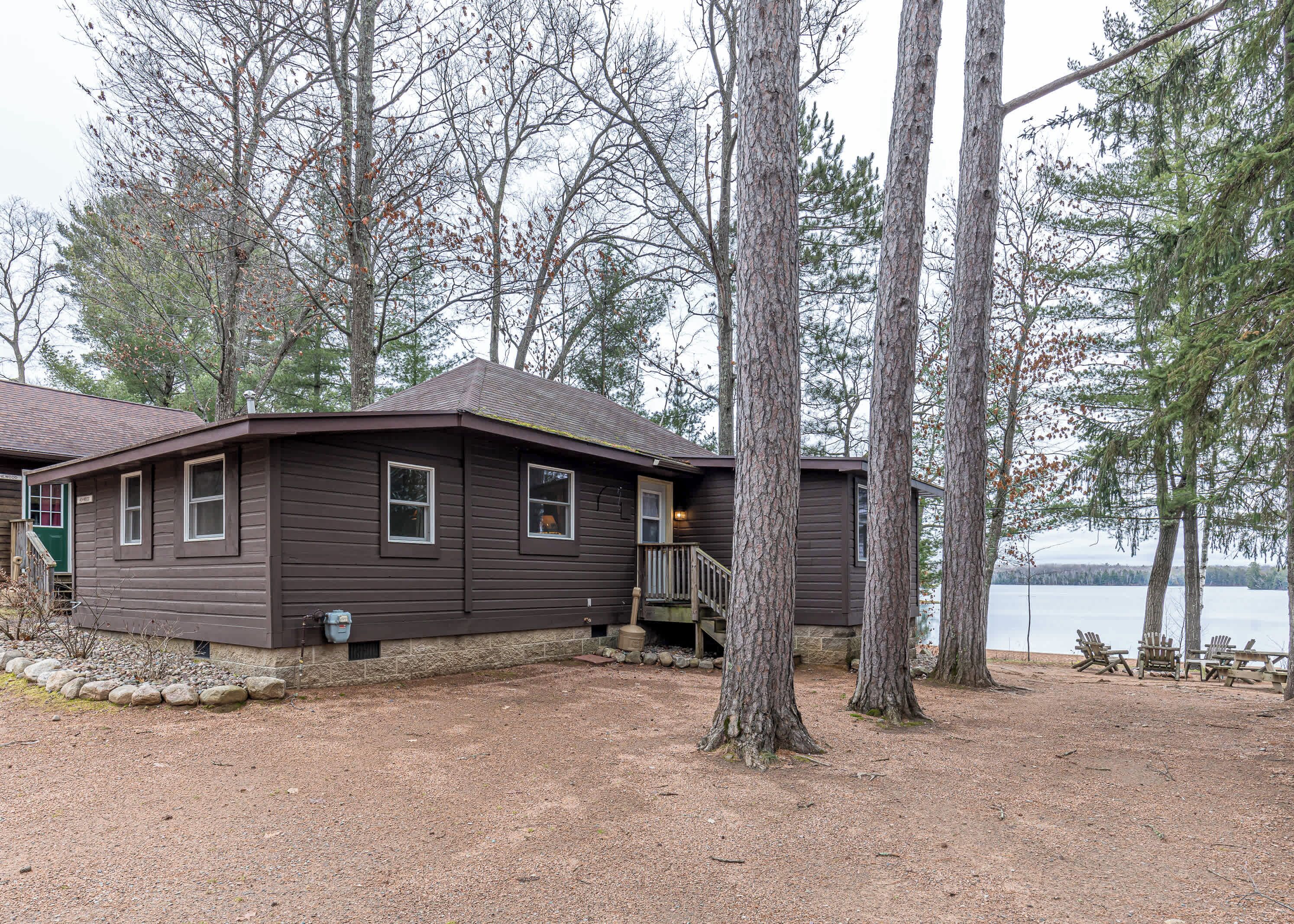 Une cabane avec des fondations en pierre, une terrasse en bois et une vue sur un lac.