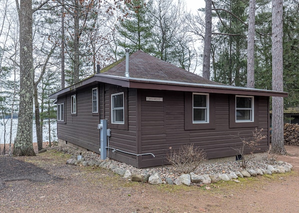 A cabin with a brown exterior, a chimney, and a sign reading 'ASHWOOD.'
