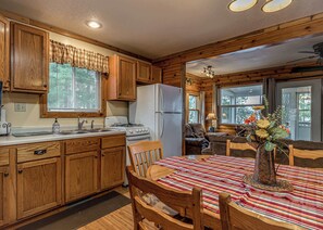A cabin-style kitchen with wooden cabinets, a stove, and a refrigerator.