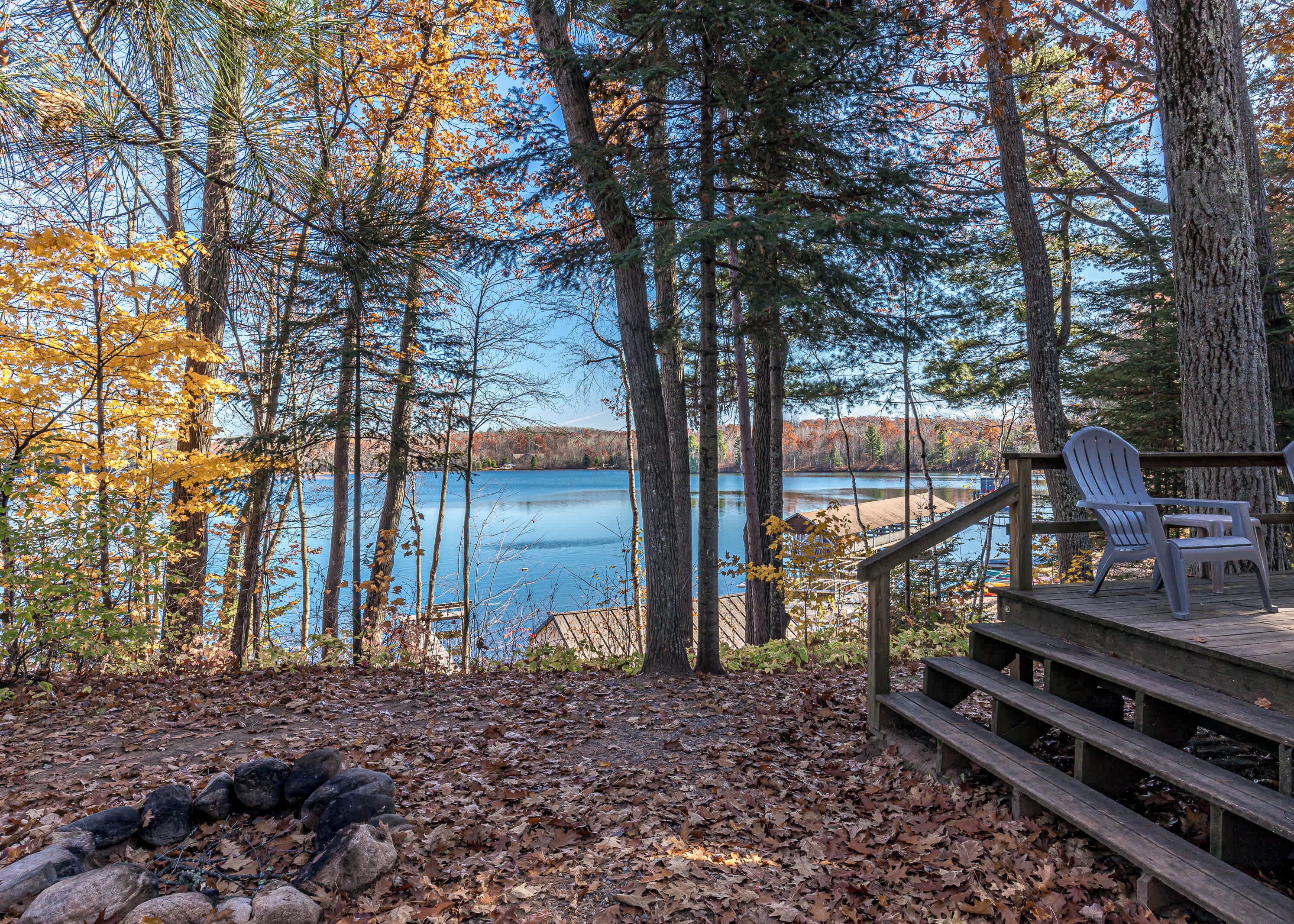 A deck with a view of a lake surrounded by trees.