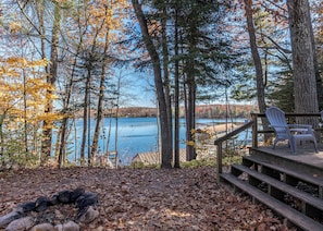 A deck with a view of a lake surrounded by trees.